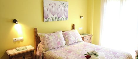 A bedroom with a bed, a nightstand, a bedside table, a ceiling fan, and a window with curtains.