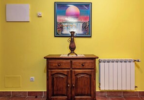 A room with a wooden cabinet, a radiator, and a painting on the wall. - Apartamentos Rurales La Viña (Cangas de Onis)
