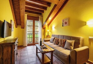 A living room with a sofa, a coffee table, a TV, and a wooden cabinet. - Apartamentos Rurales La Viña (Cangas de Onis)