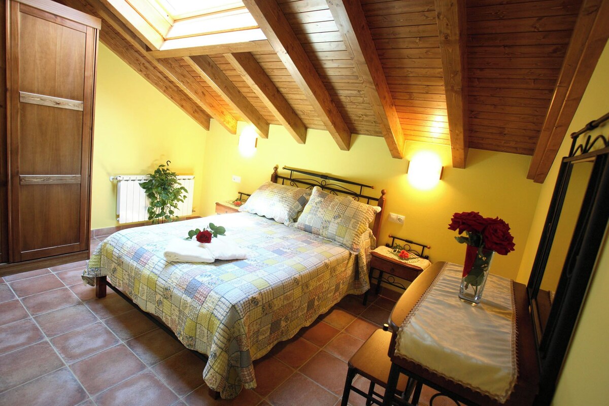 A bedroom with a bed, bedside table, chair, and a mirror.