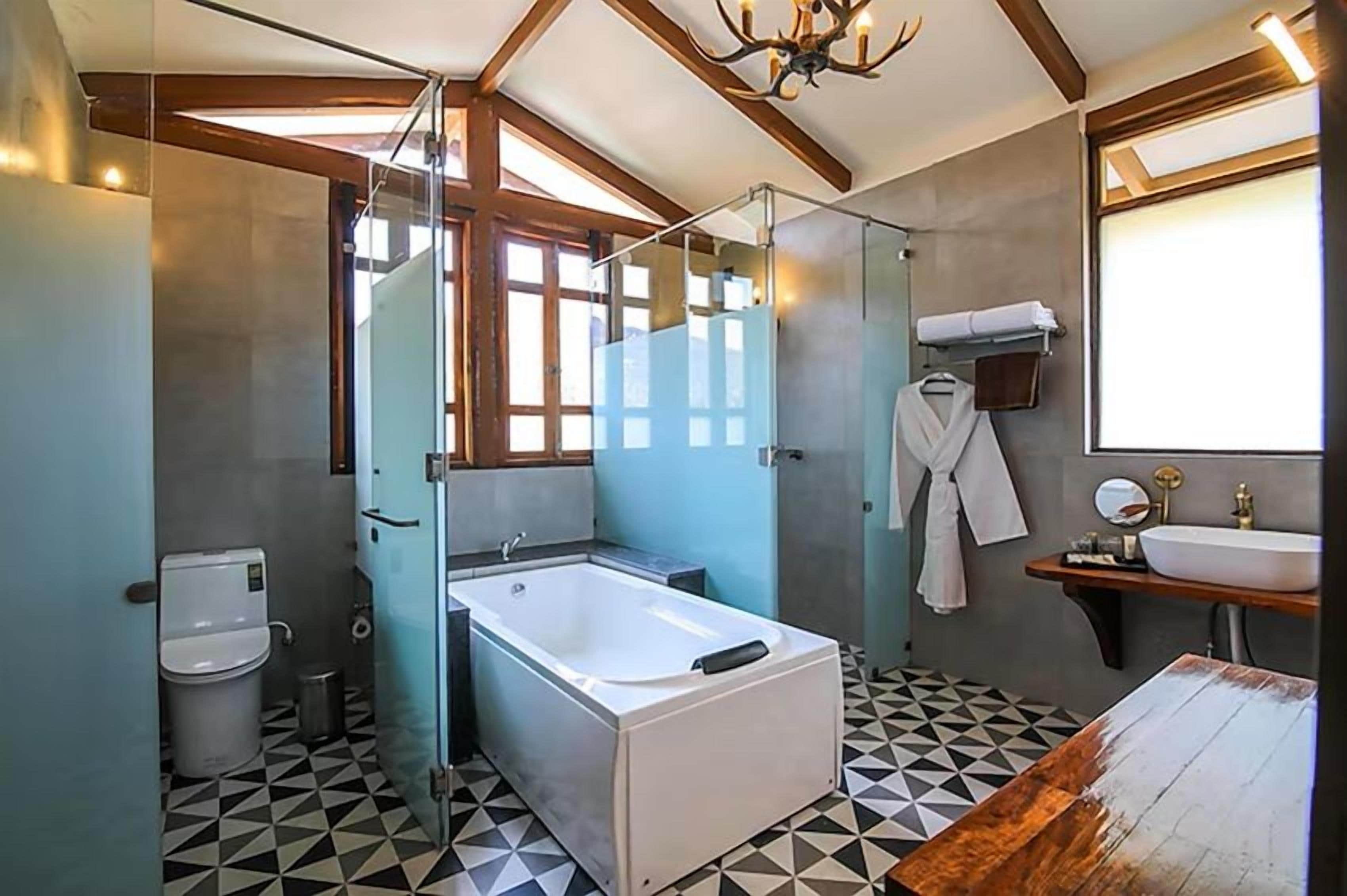A modern bathroom with a glass-enclosed shower, a freestanding bathtub, a sink with a mirror, and a wooden vanity.