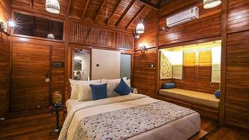 A wooden cabin room with a bed, a bench, and a mirror.