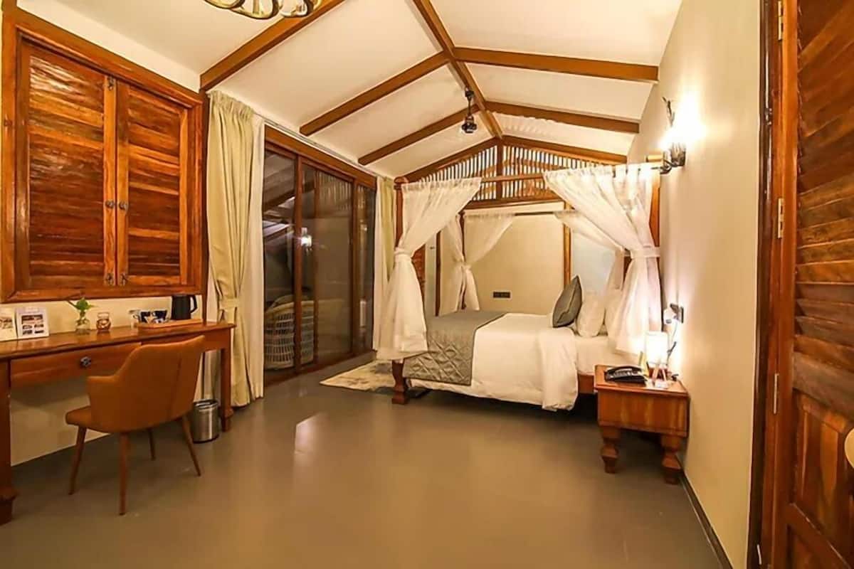 Une chambre à coucher avec un lit à baldaquin, une armoire en bois, un bureau, une chaise et une petite table de chevet.