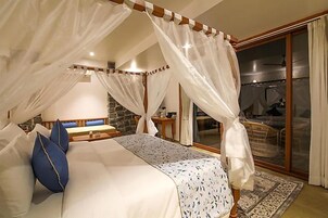 A bedroom with a canopy bed, a stone accent wall, and a view of the outside.