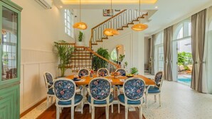 A dining area with a wooden table and chairs, a staircase, and a view of a pool. - Elivaas Vacasa - Goa (Candolim)