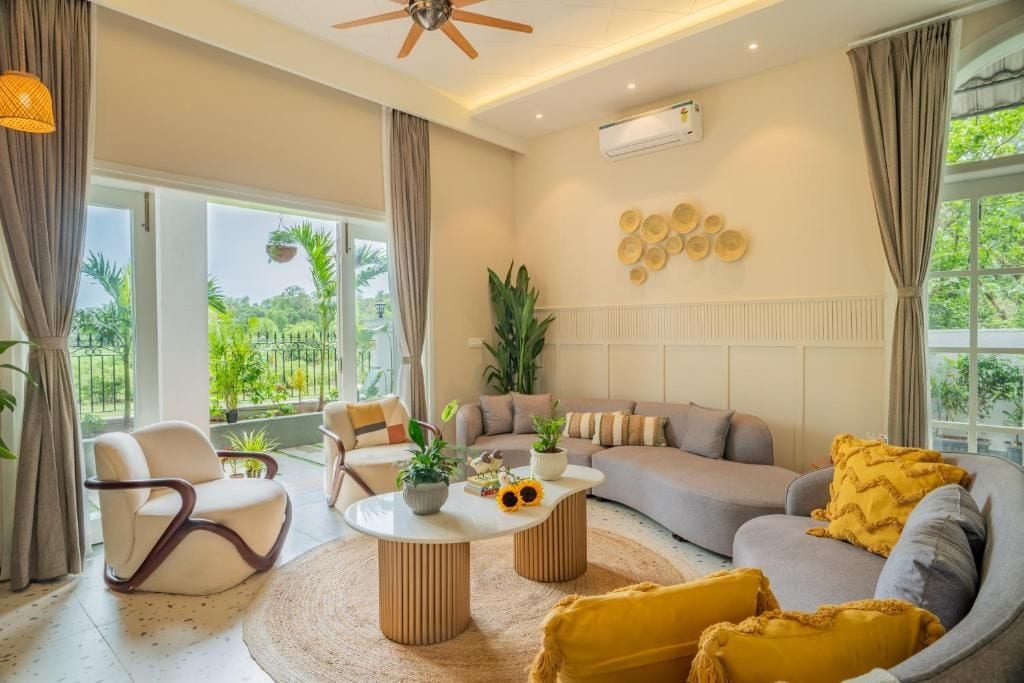 A modern living room with a sofa, armchairs, a coffee table, and a ceiling fan.