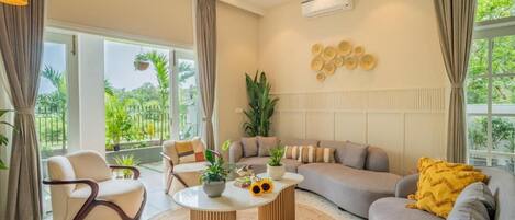 A modern living room with a sofa, armchairs, a coffee table, and a ceiling fan.