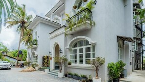 A white building with arched windows and balconies with plants. - Elivaas Vacasa - Goa (Candolim)