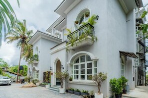 A white building with arched windows and balconies with plants. - Elivaas Vacasa - Goa (Candolim)