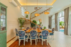 Un'area pranzo con tavolo e sedie in legno, una scala e vista su una piscina.