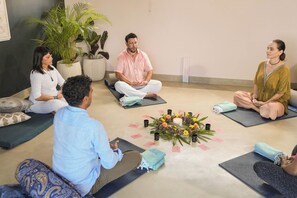 A group of people sitting on yoga mats in a room with potted plants and a decorative centerpiece. - Ayuda Sanctuary Boutique Negombo (Negombo)
