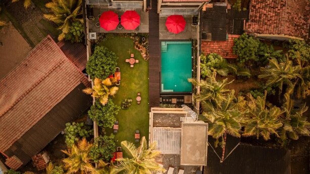 Vista aérea de una propiedad con piscina, mobiliario exterior y palmeras.