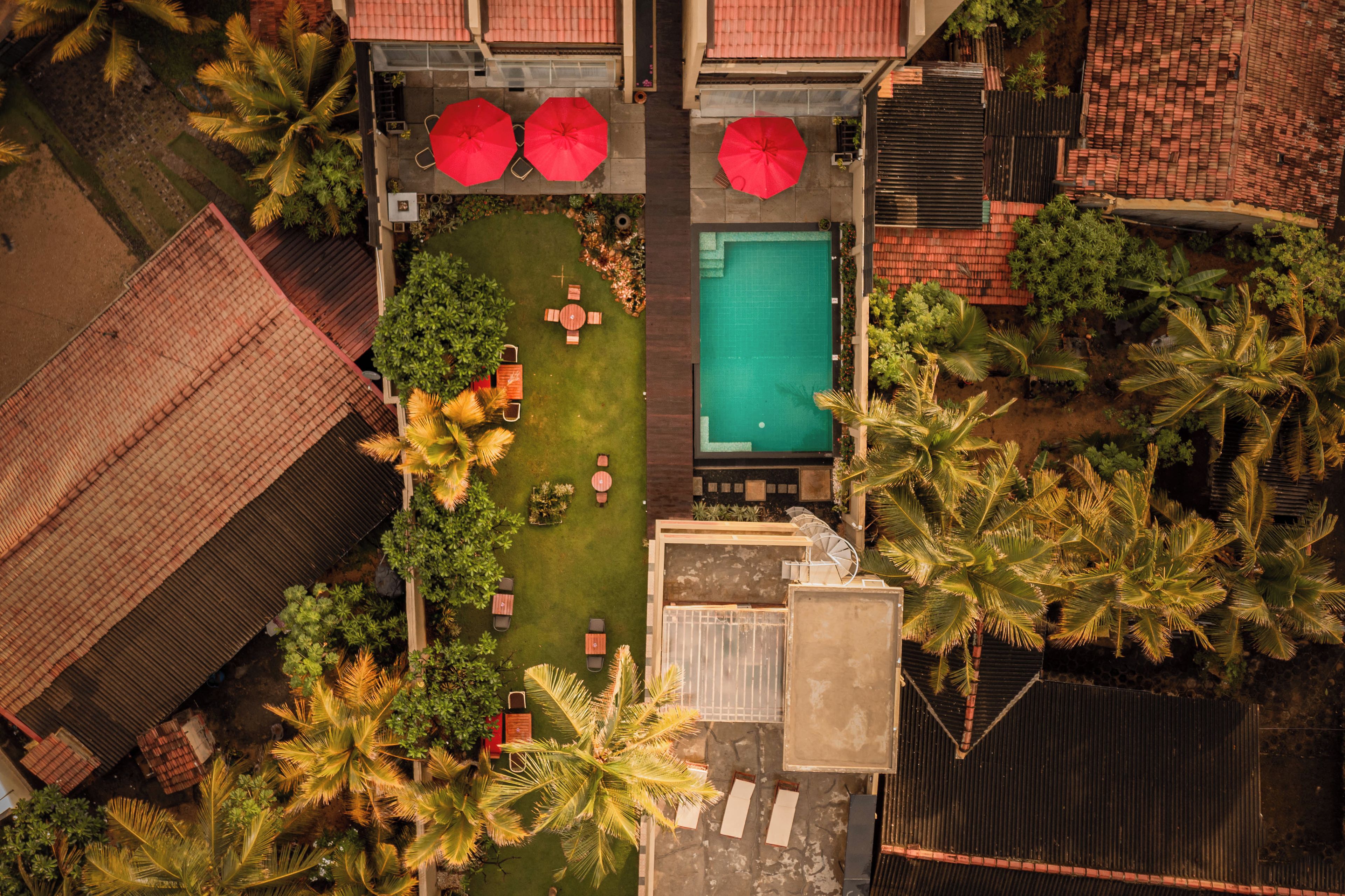 An aerial view of a property with a swimming pool, outdoor seating, and palm trees.