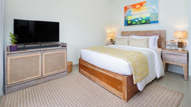 A bedroom with a bed, a television, a nightstand, and a wall-mounted painting. - Ayuda Sanctuary Boutique Negombo (Negombo)