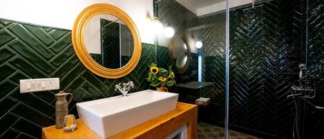 A bathroom with a wooden vanity, a large mirror, a sink, and a shower area.