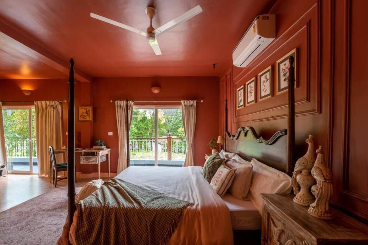 A bedroom with a bed, a desk, a chair, a ceiling fan, and a window with curtains.