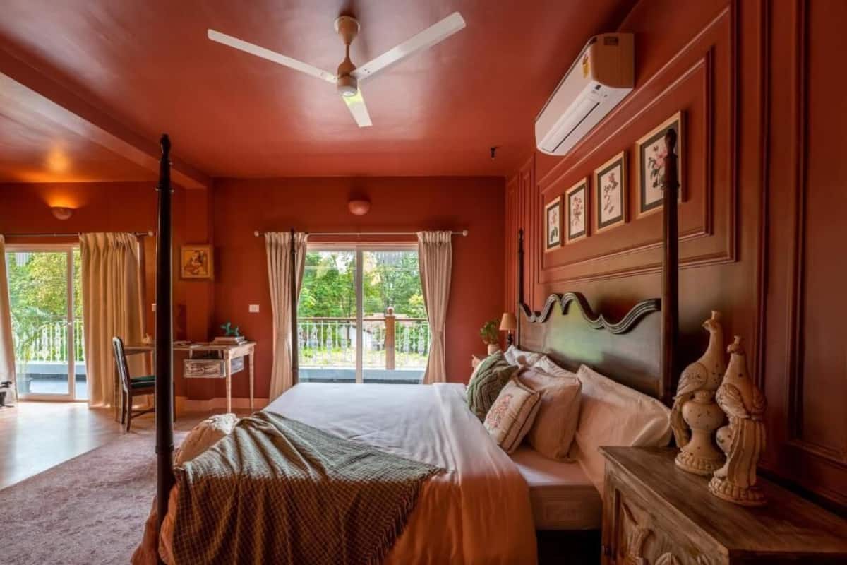A bedroom with a bed, a desk, a chair, a ceiling fan, and a window with curtains.