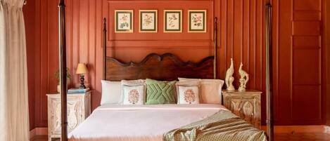 A four-poster bed with a wooden headboard, a bedside table with a lamp, and a wall-mounted air conditioner.