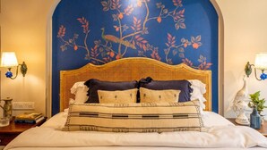 A bed with a woven headboard, a decorative wall mural, and bedside lamps. - Elivaas Bludoor - Goa (Assagao)
