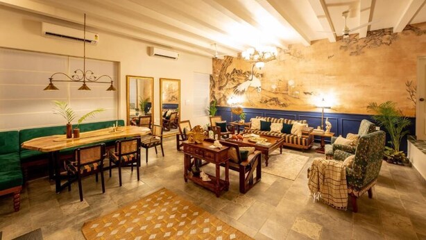 Una habitación con una mesa de comedor, sillas, sofás y un gran mural en la pared.
