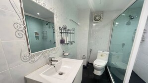 Une salle de bain moderne avec un lavabo blanc, une douche à parois de verre et des toilettes.