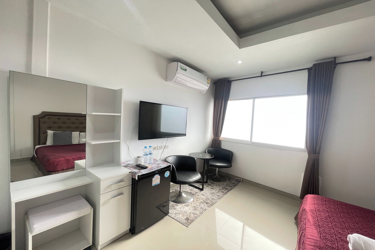 Une chambre d’hôtel avec un lit, un bureau et une chaise, une télévision et une fenêtre avec des rideaux.