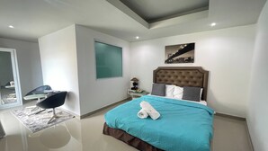 A modern bedroom with a large bed, a nightstand, a chair, and a cityscape artwork on the wall. - W-9 Hotel By Zuzu (Pattaya)