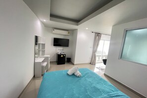 A modern hotel room with a bed, a TV, a small desk, and a window with curtains. - W-9 Hotel By Zuzu (Pattaya)