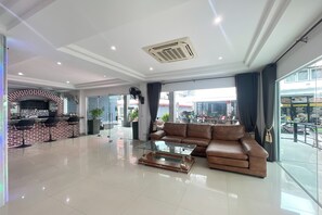 A spacious living area with a leather sofa, a glass coffee table, and a brick-patterned bar area with stools. - W-9 Hotel By Zuzu (Pattaya)