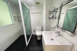 Een kleine badkamer met toilet, wastafel en een douchecabine van glas.