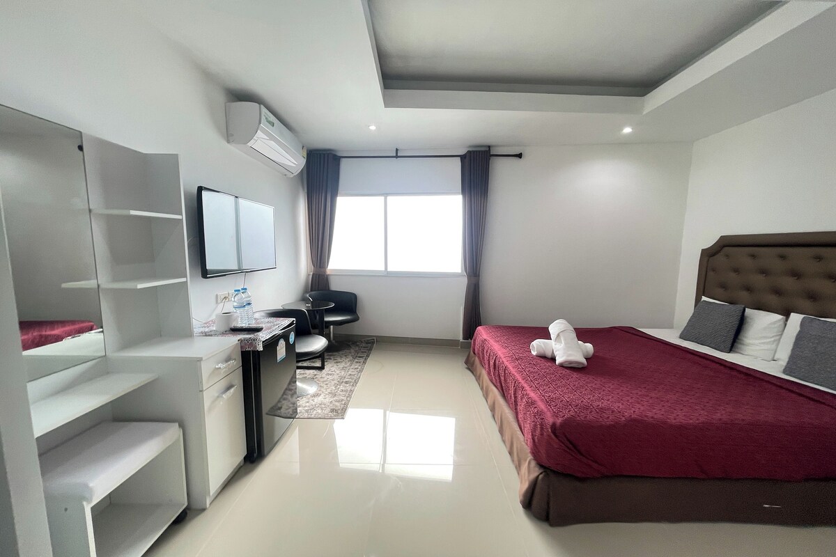 Een moderne hotelkamer met een bed, een bureau, een stoel en een televisie.