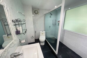 A modern bathroom with a glass shower enclosure, a white toilet, and a large mirror with a decorative frame. - W-9 Hotel By Zuzu (Pattaya)