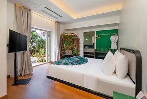 Ein Hotelzimmer mit Bett, Flachbildfernseher, grüner Wand mit dekorativem Spiegel und Blick ins Freie.