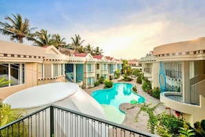 A resort with multiple-story buildings, a central swimming pool, and surrounding greenery.