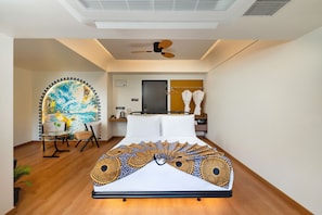 A modern bedroom with a bed, a ceiling fan, a wall-mounted TV, and a bathroom visible through an open door.