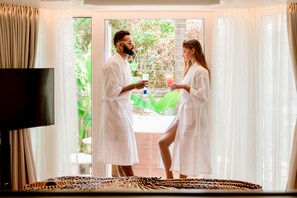 A room with a large window, a flat-screen TV, and a bed with a leopard print blanket. - The Orchid Passaros (Benaulim)