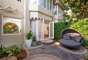 A courtyard with a stone pathway, a cushioned outdoor seating area, and a potted plant arrangement. - The Orchid Passaros (Benaulim)
