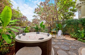 A hot tub surrounded by greenery and stone paths.