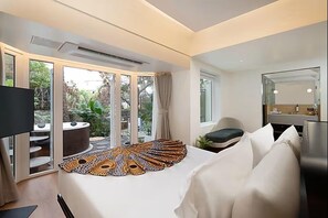 A modern hotel room with a large bed, a sitting area with a view of the garden, and a separate bathroom with a mirror. - The Orchid Passaros (Benaulim)