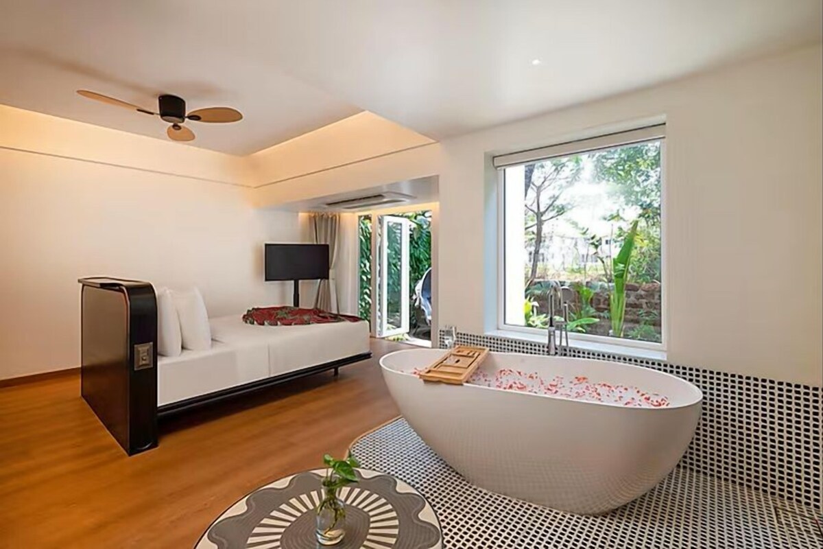A modern bathroom with a freestanding bathtub, a sofa, and a television.