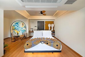 A modern bedroom with a bed, a ceiling fan, a painting, and a chair. - The Orchid Passaros (Benaulim)