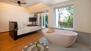 A modern bathroom with a freestanding bathtub, a sofa, and a television. - The Orchid Passaros (Benaulim)
