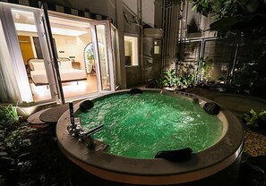 A hot tub with a circular shape and a greenish water color, surrounded by plants and rocks. - The Orchid Passaros (Benaulim)