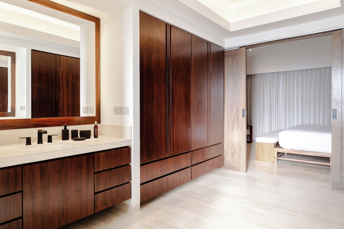Une chambre à coucher moderne, dotée d’une grande armoire, d’une coiffeuse avec un miroir et d’un lit avec une tête de lit.