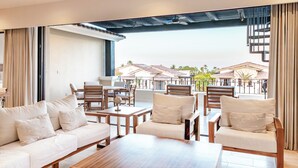 A modern lounge area with a sofa, chairs, and a coffee table. There is a view of a building with a tiled roof and palm trees in the background. - Bohari (San José del Cabo)