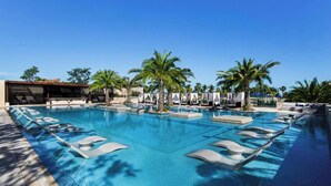 A large, clear swimming pool with lounge chairs and palm trees. - Bohari (San José del Cabo)