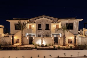 A two-story house with a stone facade, multiple windows, and a well-lit entrance. - Bohari (San José del Cabo)