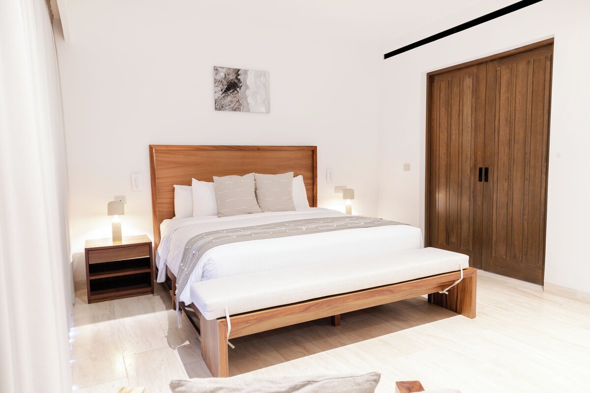 A bedroom with a wooden bed, bedside tables, a nightstand, and a wardrobe.