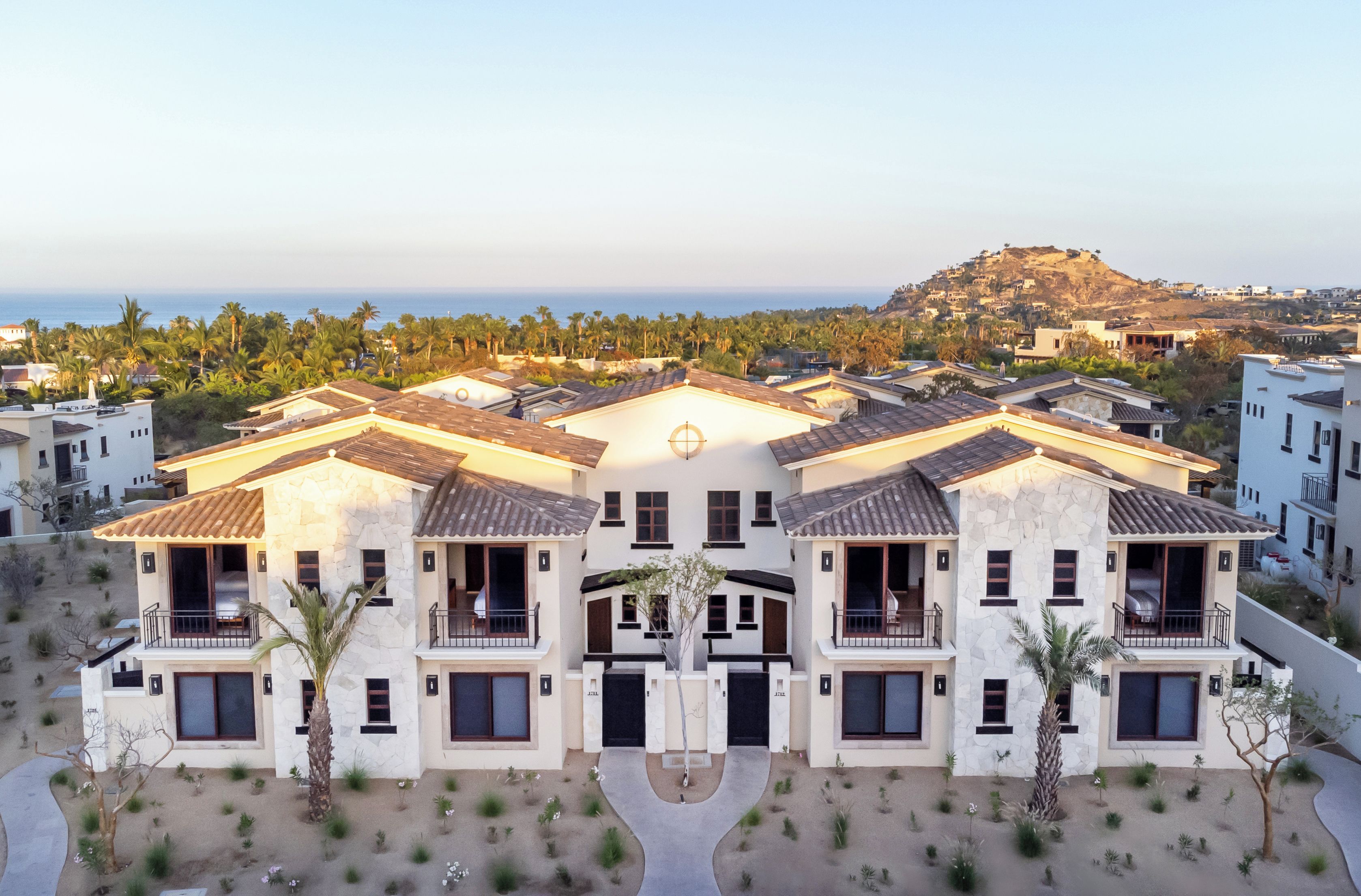 A multi-story building with a central courtyard, balconies, and a view of the ocean.