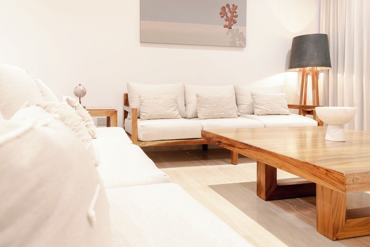 Un salon moderne avec une table basse en bois, un canapé blanc et une lampe.